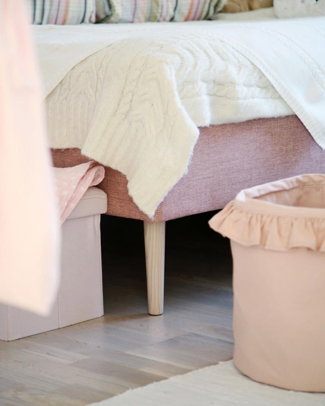 lit IKEA avec pieds en bois clair dans une chambre douce et féminine avec textiles superposés