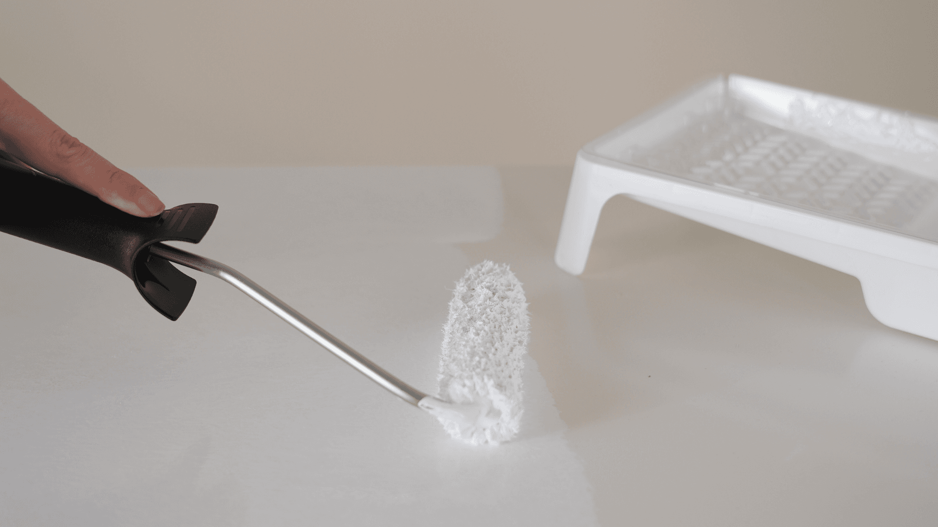 Application de peinture blanche sur un meuble avec un petit rouleau – relooking DIY