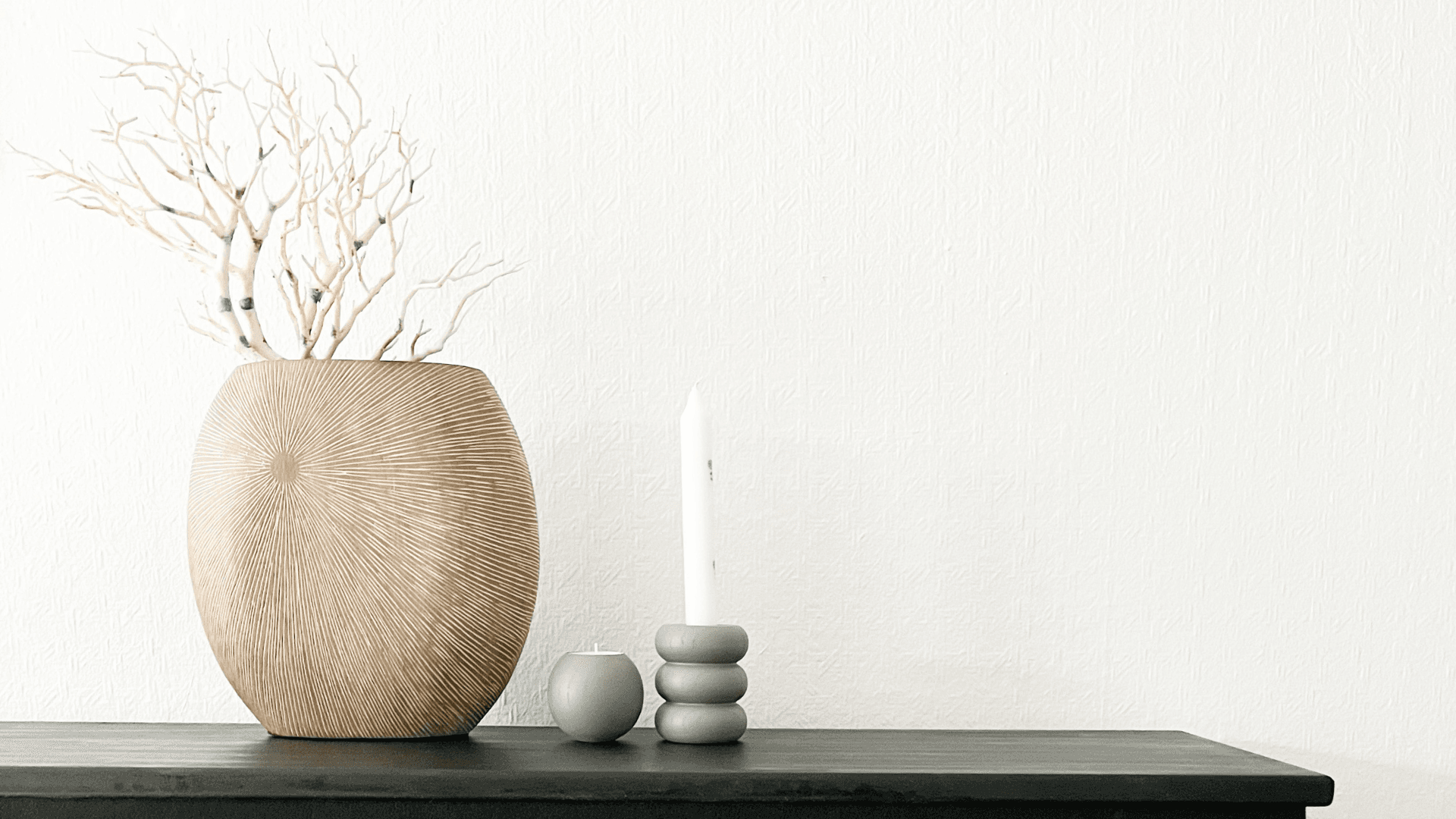 Minimal Scandinavian vignette with textured beige vase, decorative branches and modern candle holders.