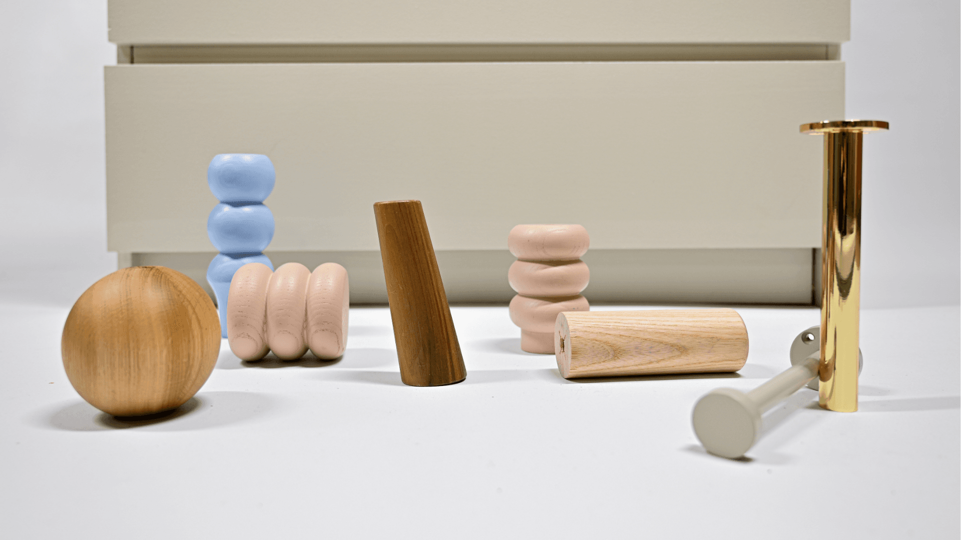 Möbelfüße aus Holz, Metall und farbigen Oberflächen vor einer IKEA MALM Kommode