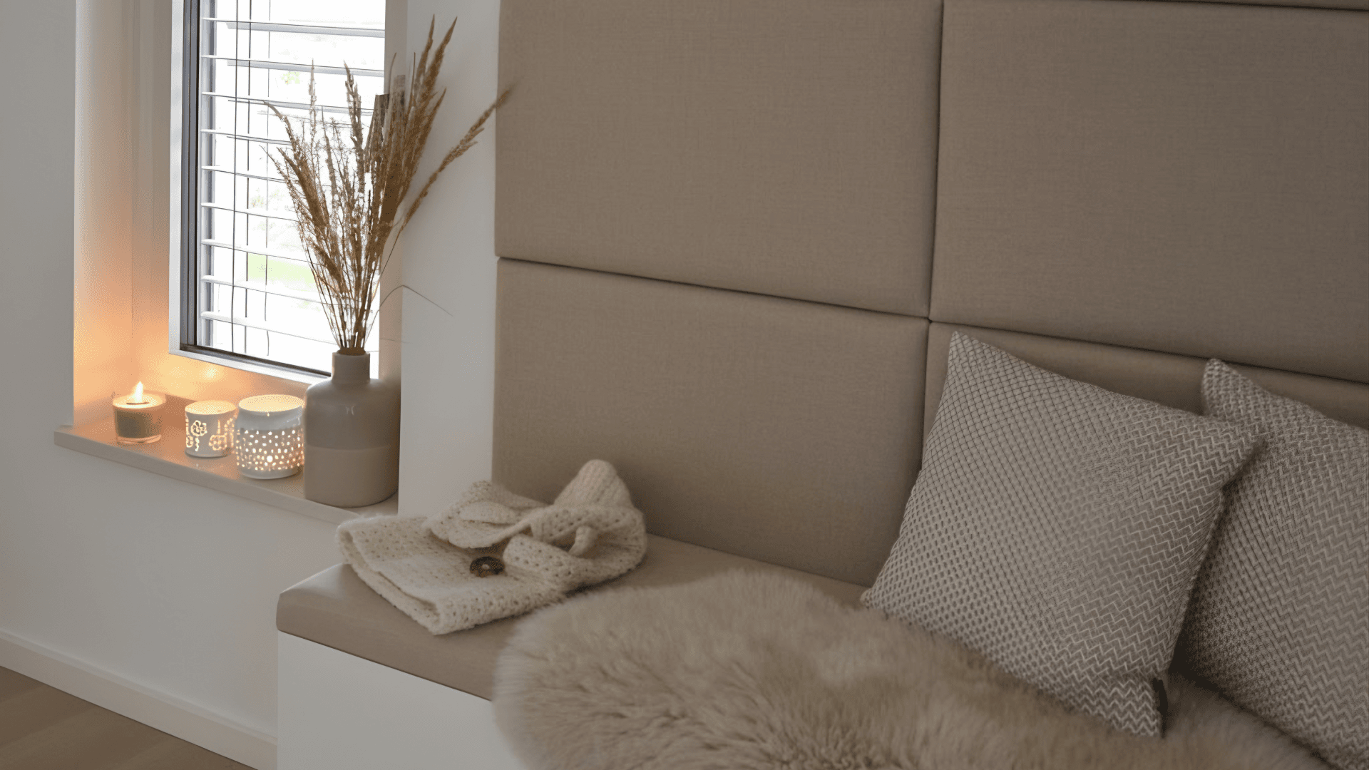 Cozy Scandinavian window nook with warm candlelight, soft neutral textiles and minimal holiday accents.